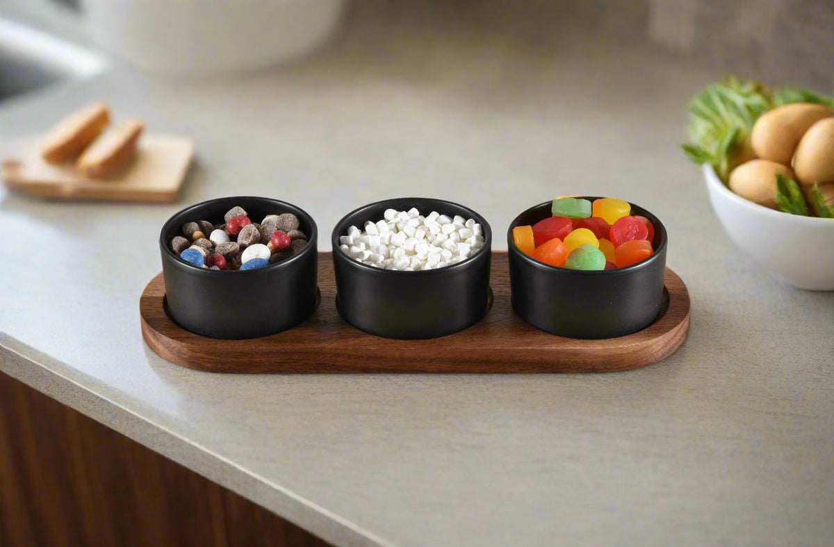 Ceramic condiment set with multiple small bowls on a wooden acacia tray, designed for serving sauces and condiments.