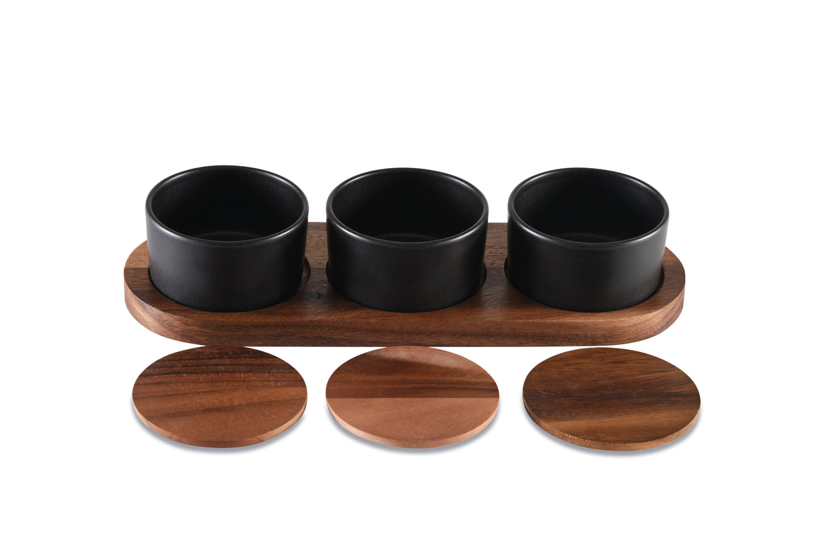 Ceramic condiment set with multiple small bowls on an acacia wood serving tray by Kalmar Home.