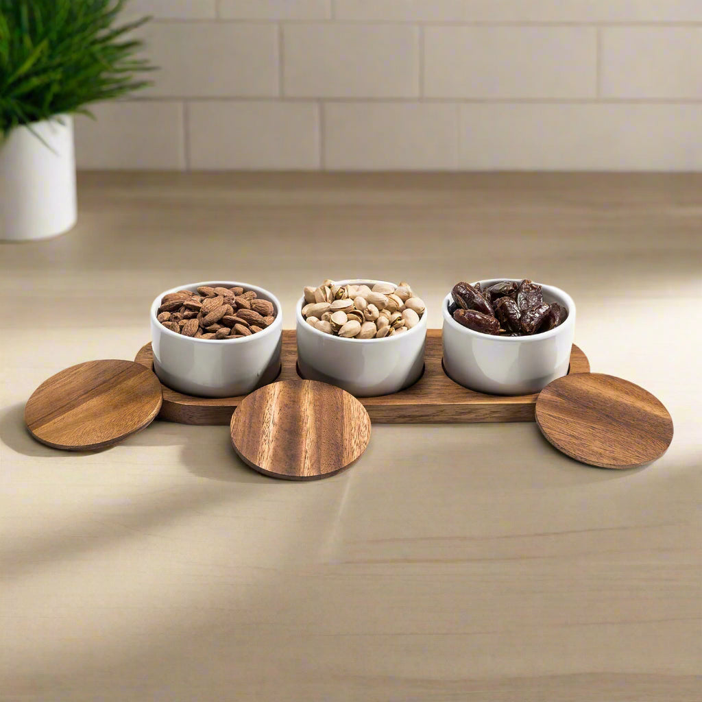Ceramic condiment set with four small bowls on an acacia wood serving tray, designed by Kalmar Home.