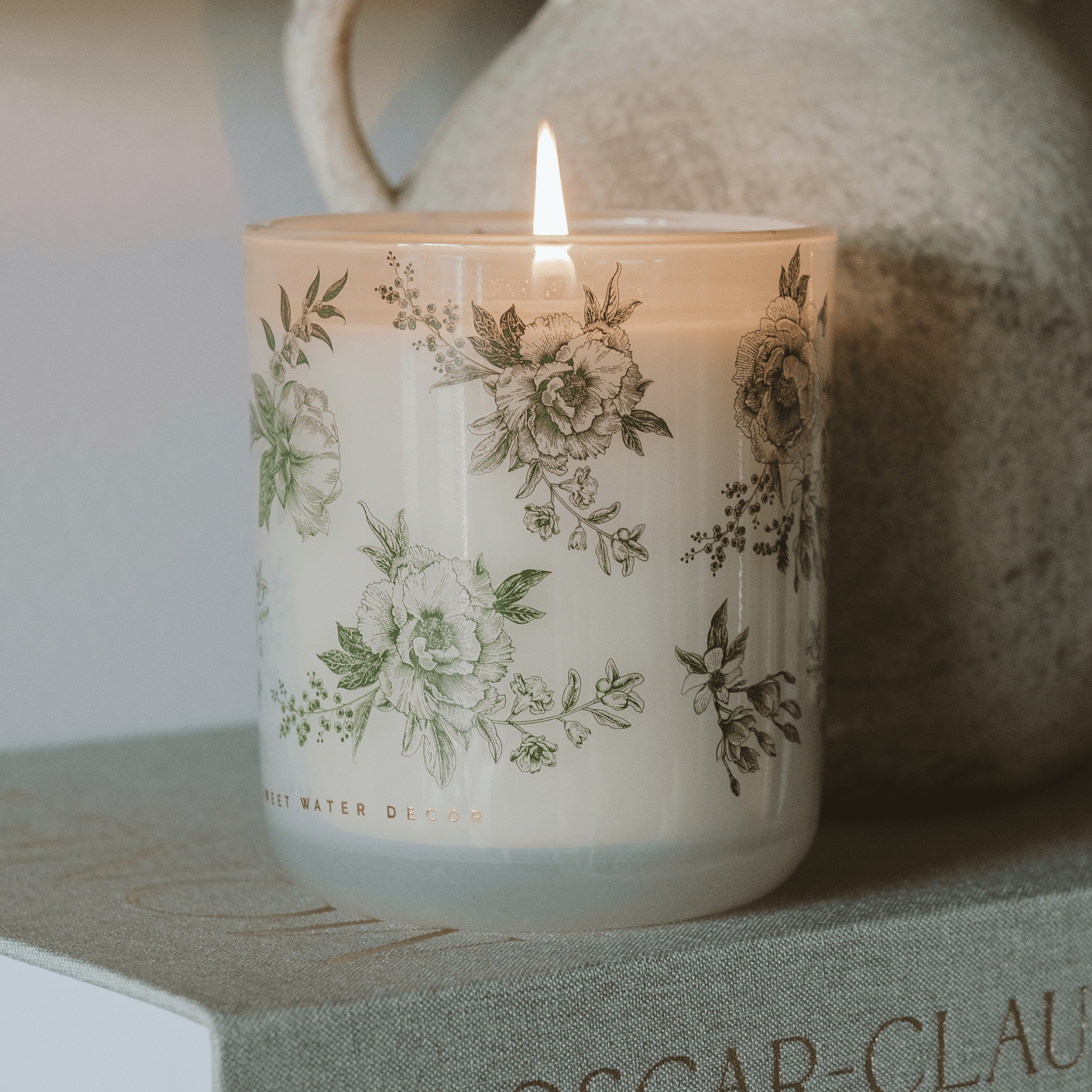 Green floral soy candle by Sweet Water Decor with lavender accents, perfect for spring home decor.