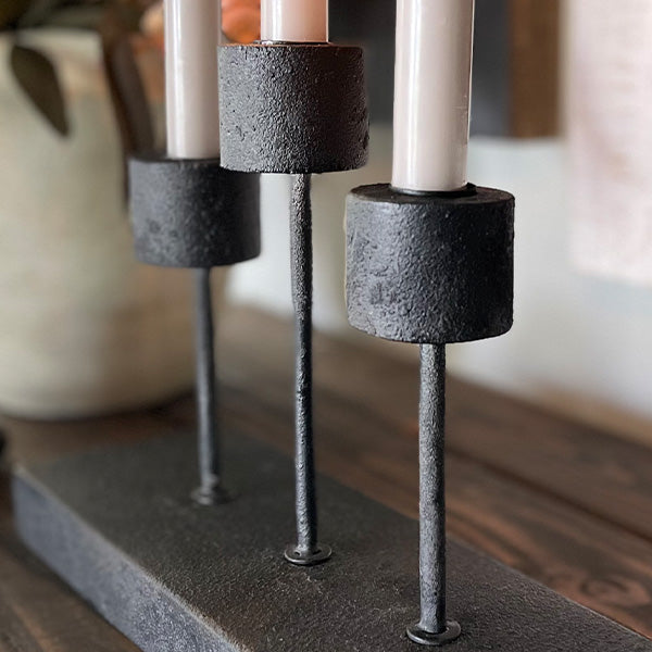 Distressed black metal candle holder with a rustic, vintage look, designed to hold pillar candles, by Decor Steals.