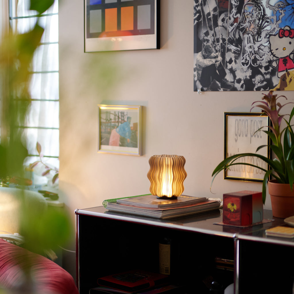 Wooj Design Mini Wavy Lamp emitting soft, smoky light with a cordless, modern wavy design on a stylish tabletop.
