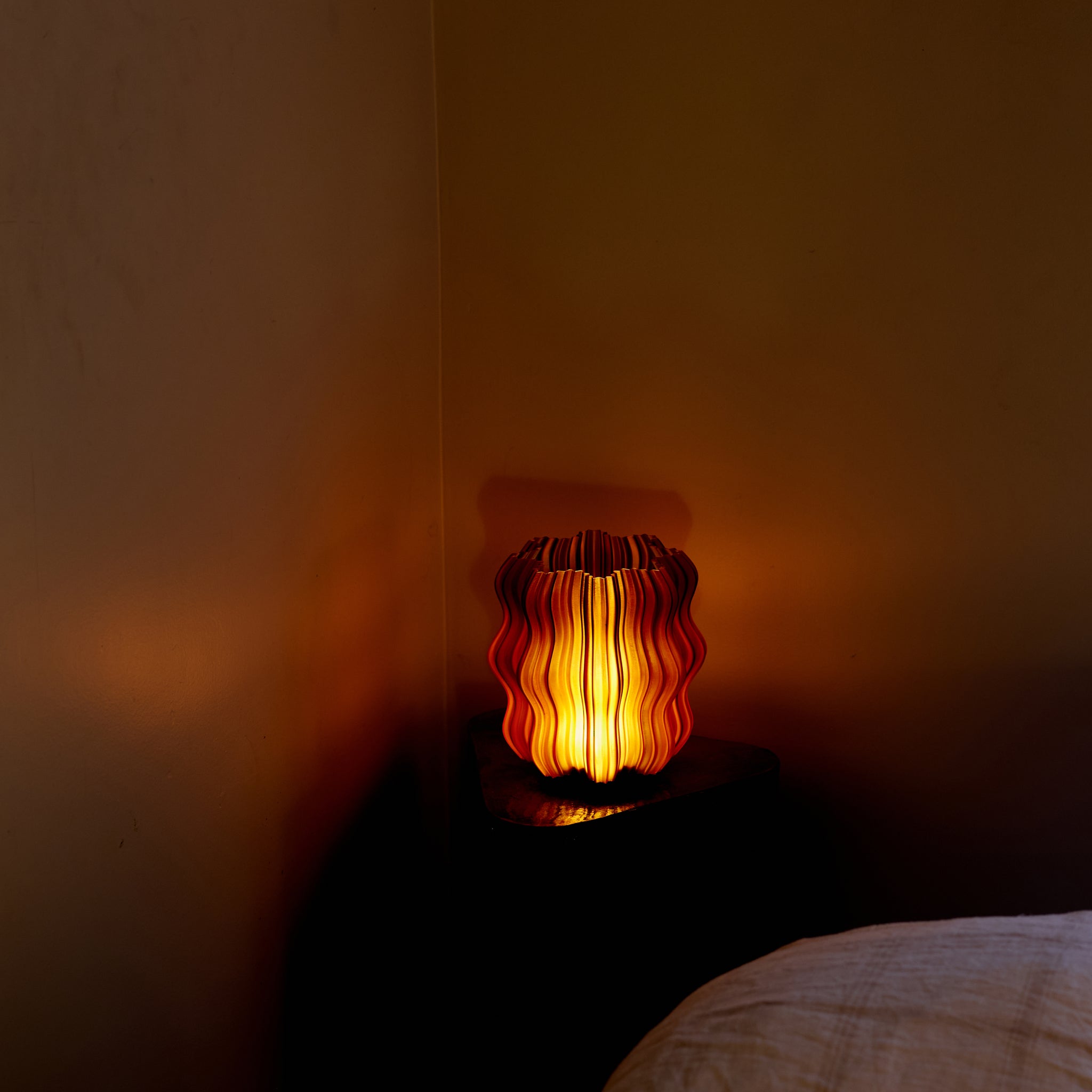 Close-up of Wooj Design Mini Wavy Lamp in amber with cordless design, showcasing its wavy textured surface and warm glow.