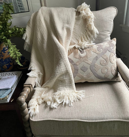 Natural cotton throw blanket from Carolina Cottons draped over a chair, showcasing soft, breathable 100% cotton fabric.