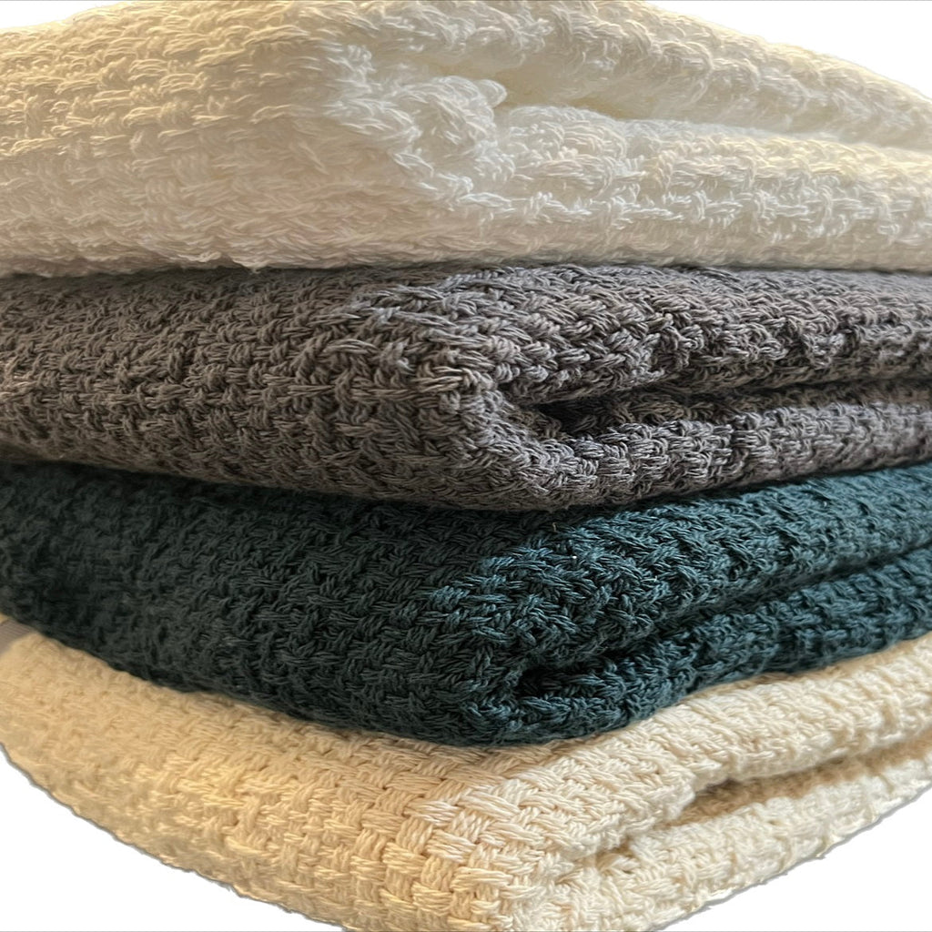 Stack of soft, 100% cotton throw blankets by Carolina Cottons, showcasing cozy, lightweight blankets in neutral tones.