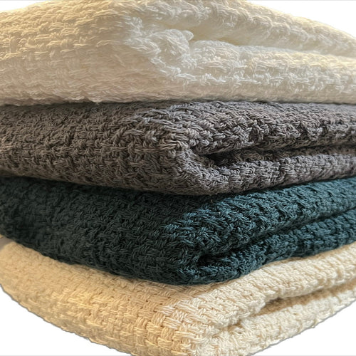 Stack of soft, 100% cotton throw blankets by Carolina Cottons, showcasing cozy, lightweight blankets in neutral tones.