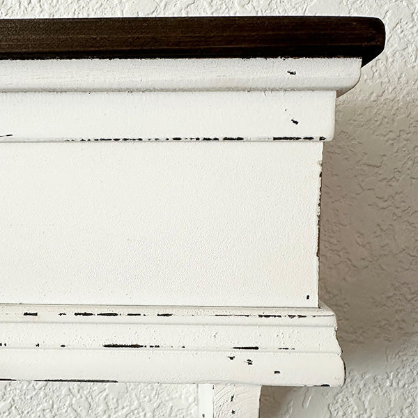 Distressed white wood wall shelf from Decor Steals with a rustic, vintage look, mounted on a wall with visible brackets.