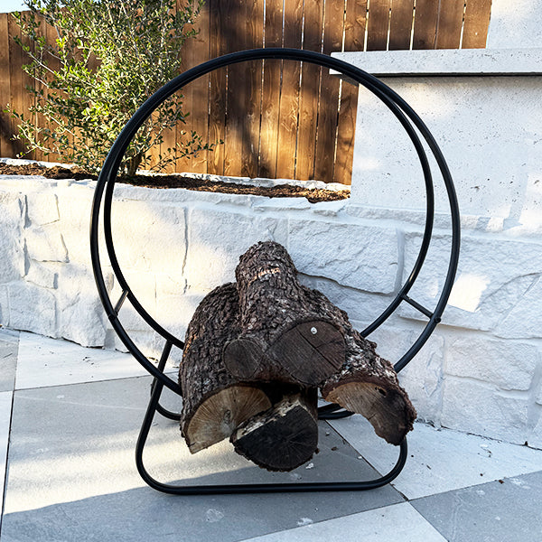 Decor Steals black iron loop fireplace log holder with wooden logs in a cozy living room setting.